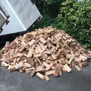 Truck dumping split firewood in driveway