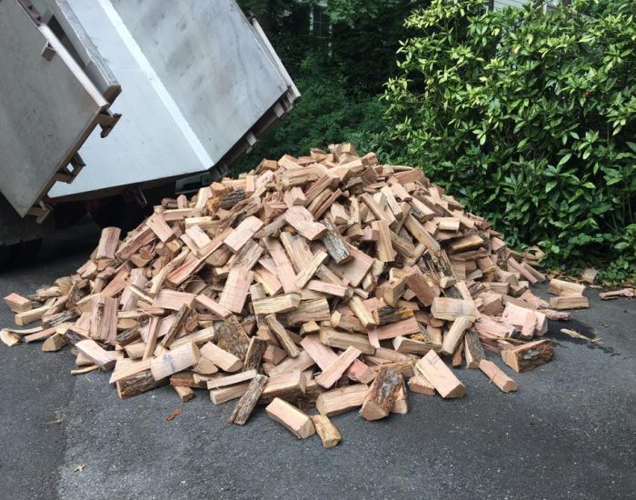 Truck dumping split firewood in driveway